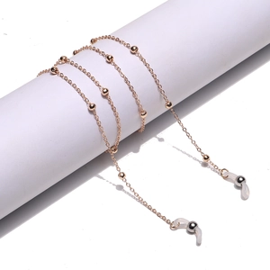 Detail of golden metal glasses chain with small beads and white silicone loops