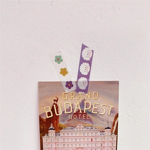 Close-up of decorative washi tape with floral and dog patterns on textured white wall
