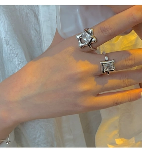 Detailed view of hand wearing 925 sterling silver rings with square clear gemstones