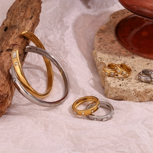 Détail d'un ensemble de bijoux en or 18 carats et argent avec zircons sur pierre beige