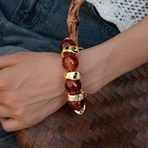 Close-up of bohemian acrylic amber beads and golden metal elements on a wrist bracelet