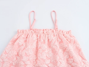 Dettaglio dell'abito rosa con texture jacquard 3D e scollo elastico a volant