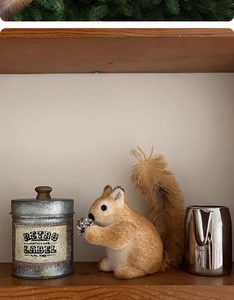 Detail of a lifelike squirrel ornament holding a pinecone on a wooden shelf decoration