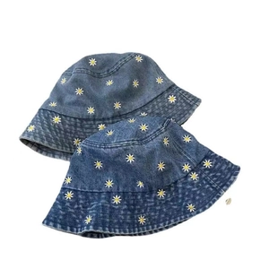 Detailed close-up of daisy embroidery on light and dark blue washed denim bucket hats