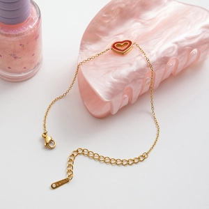 Detail of gold stainless steel heart bracelet with red enamel and lobster clasp closure