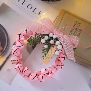 Détail d'une couronne de cloches de Noël roses avec épines de pin, baies et étiquette