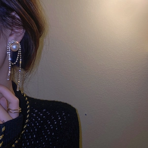Macro side view of long silver needle tassel earrings with pearls and rhinestones