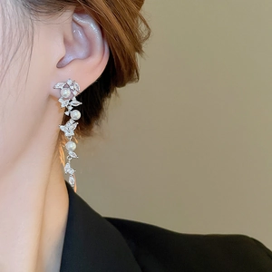Detail view of pearl tassel earrings featuring clear zircon leaves on female model