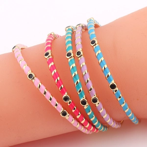 Detail of colorful enamel bangles with striped patterns and evil eye motifs on gold metal