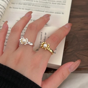 Detailed view of silver pearl bead ring worn by a model against an elegant book background