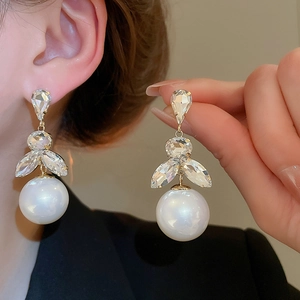 Detail of silver needle pearl tassel earrings with faceted crystals and golden metal accents