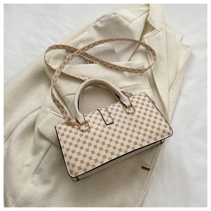 Top view of beige leather bag with geometric patterns, gold hardware and slim strap