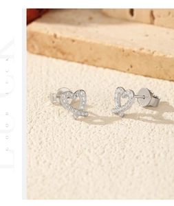 Detail showing shimmering heart-shaped silver earrings with small zircon stones on stone