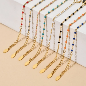 Detail of colorful enamel bead gold chains with S.Steel tags on a minimalist stand
