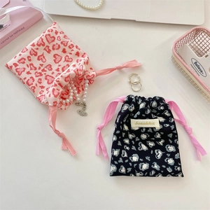 Detailed view of pink and navy drawstring pouches with heart leopard print and accessories