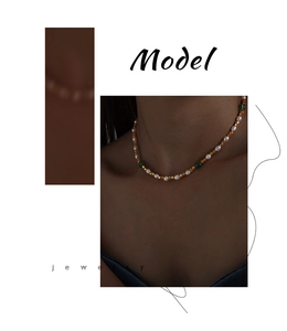 Detail of beaded necklace featuring white pearls, gold spacers, and green gemstones
