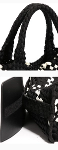 Detail of woven tote bag showing round black and white striped handles and velcro closure
