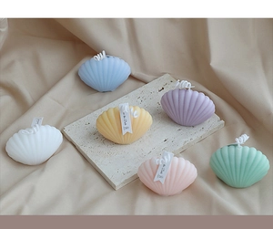 Top view of colorful seashell-shaped scented candles on a textured satin background
