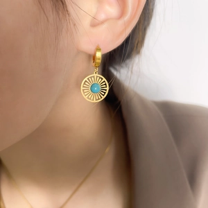 Vintage gold hollow sunburst earrings with turquoise pendant on female model