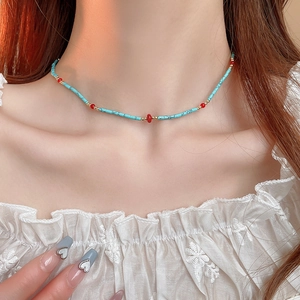 Detail of bohemian turquoise beaded necklace with gold and red accents on neck