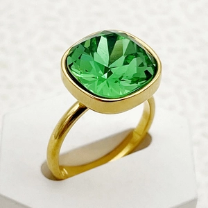 Gros plan d'une bague avec pierre précieuse verte carrée et finition dorée