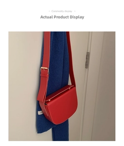 Detail of red PU leather saddle bag featuring gold hardware and wide shoulder strap