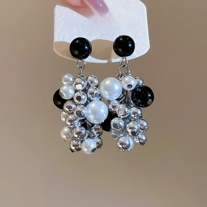 Detail of silver S925 needle earrings with white pearls and black beaded tassels