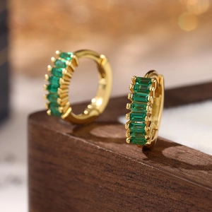 Macro shot of 925 silver huggie earrings with rectangle emerald green zircon stones