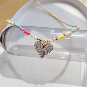 Macro shot of bohemian heart pendant with rainbow clay beads and natural pearls