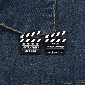 Detail of film slate enamel pins on denim with creative cinema quotes and metal texture