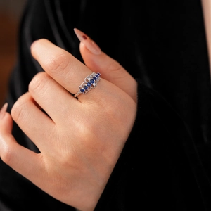 Gros plan sur une bague en dentelle avec des zircons bleus et blancs au doigt