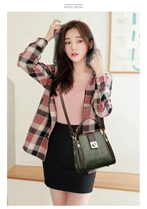 Deep green bucket bag with brown contrast trim and golden lock shown on a female model