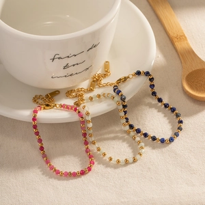 Three colorful beaded bracelets with gold accents on a white cup tray in a cozy home setting