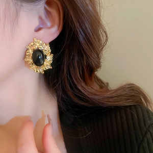 Detail of vintage French gold leaf earrings featuring a polished black oval centerpiece