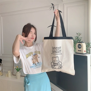 Detail of canvas tote bag featuring cute bear embroidery and lucky text on fabric