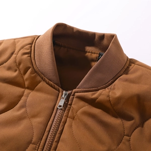 Detail of caramel brown quilted jacket with ribbed collar and silver metal zipper