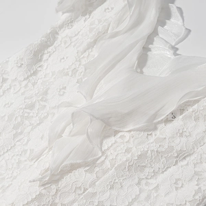 Détails de la robe blanche montrant la dentelle délicate et les volants en mousseline