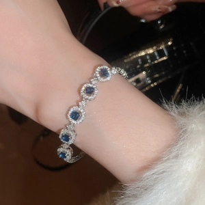 Detailed close-up of a silver bracelet with five halo-set blue square zircon gemstones