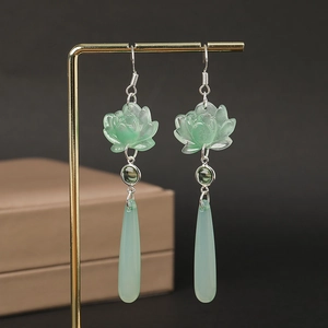 Detailed macro view of light green lotus tassel earrings with teardrop pendants
