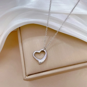 Detailed view of silver heart pendant on chain draped over a jewelry box with silk