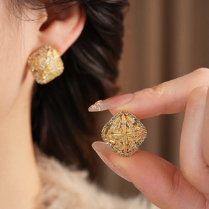 Detail of square geometric stud earrings with pave set zircons worn on earlobe