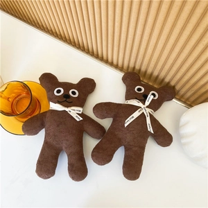 Close-up of two mini brown teddy bears with neck ribbons on a warm tone desk