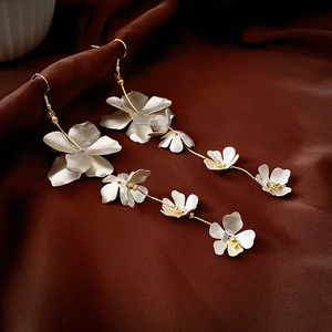 Detail von langen floralen Fransenohrringen mit weißen matten Blüten und Goldketten