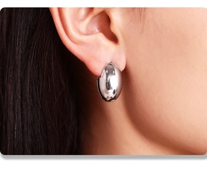 Close-up of polished silver oval hoop earring showing smooth metallic texture and fit