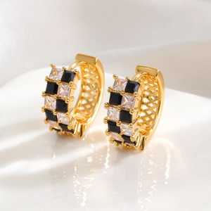 Macro shot of gold checkered hoop earrings featuring black and white cubic zirconia