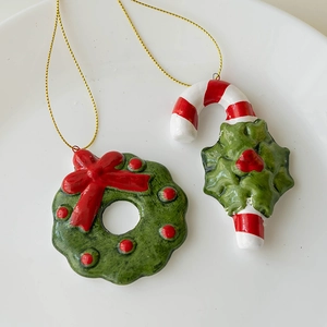 Christmas ceramic wreath and candy cane ornaments with golden strings on a white plate