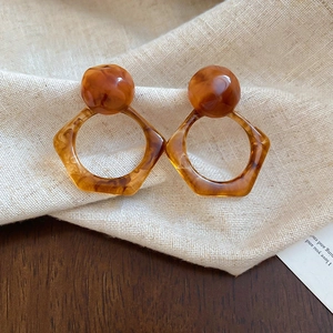 Detailed view of 14K gold plated earrings with brown tiger eye resin on linen fabric