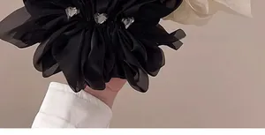 Detail der schwarzen Chiffon-Blumen-Haarklammer mit drei herzförmigen grauen Kristallen