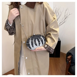 Macro detail of zebra pattern rhinestone clutch bag with silver chain strap and snap