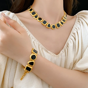 Detail shot of vintage gold necklace and bracelet set with black stones on model